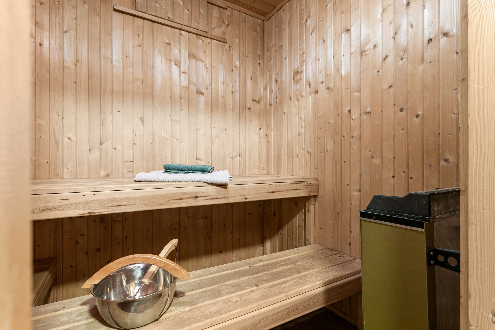 Compact pine sauna with a small heater, bench and bucket in a Napa home